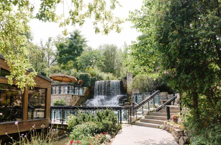 A large garden with a waterfall and stone pathways throughout.