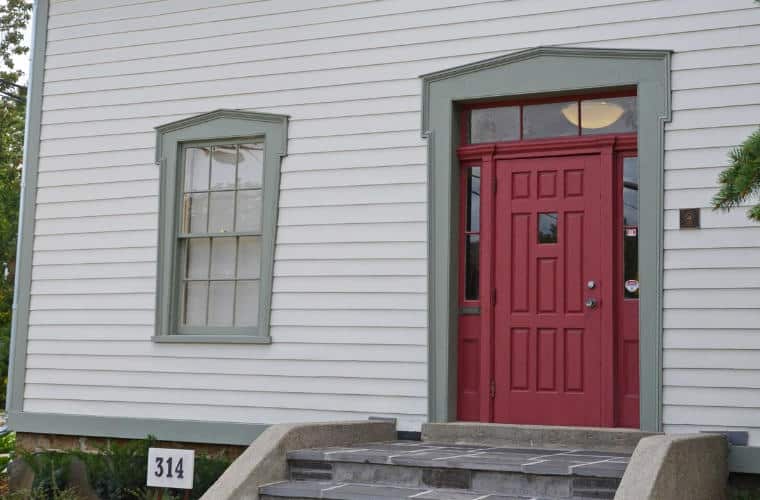 A building with white siding and a red door.