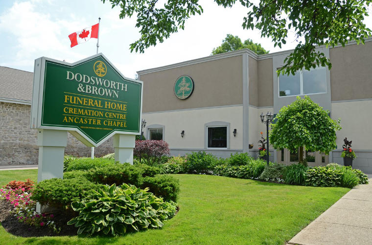 A large beige and cream building with a sign for Dodsworth and Brown Funeral Home on the large front lawn.