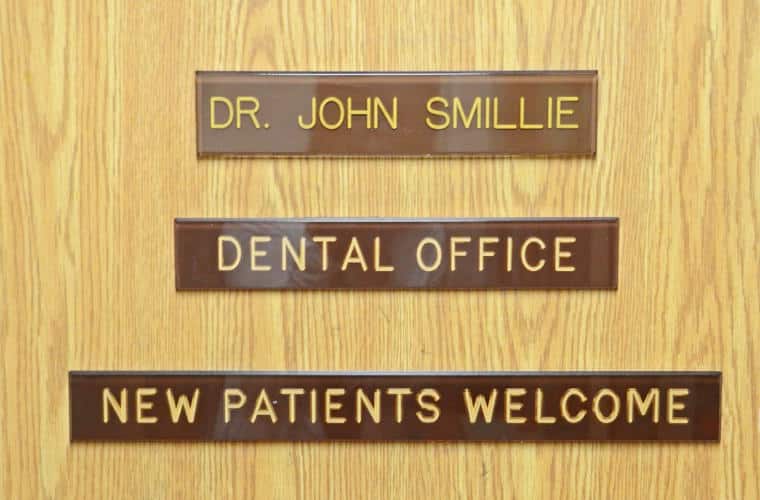 A wood door with a plaque for Dr. John Smillie Dental office on it.