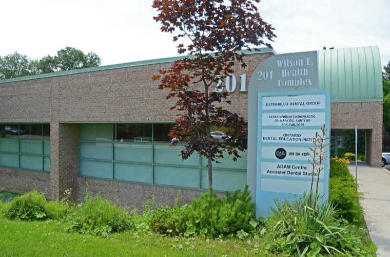 An orange brick building with a pylon sign out front with Estrabillo Dental Group on it.
