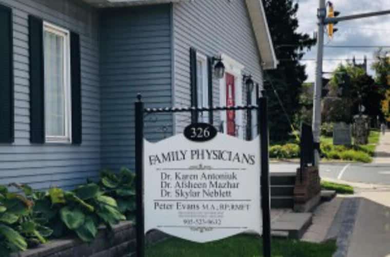 A building with blue siding and a sign for Family Physicians on the front lawn.