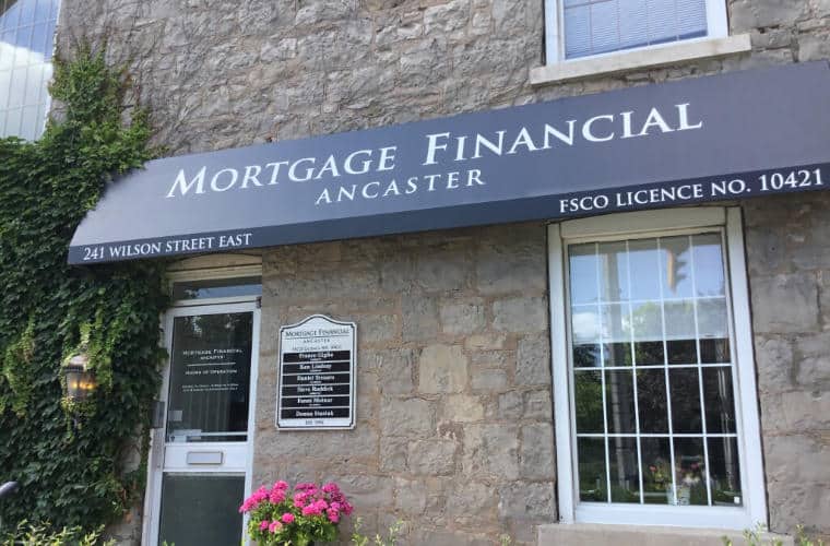 A rough hewn beige stone building with sign for Mortgage Financial Ancaster on the awning above the entrance.