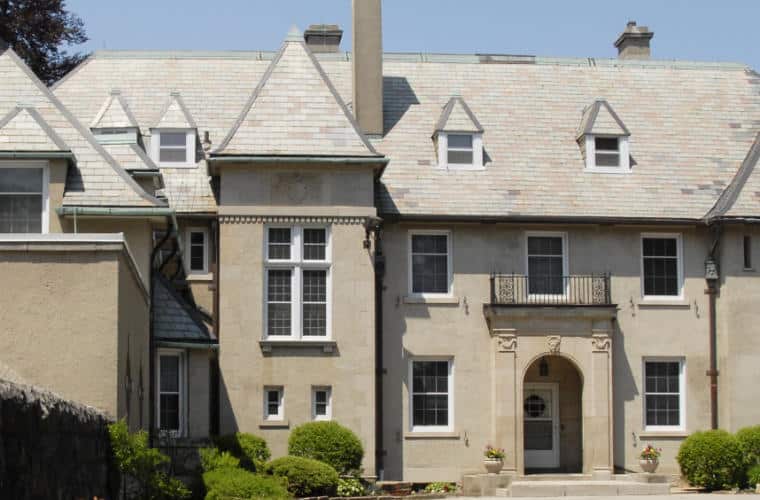 A large beige smooth stone building with arched entrance and white trim.
