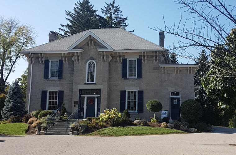 A large grey rough hewn stone house with shutter windows.