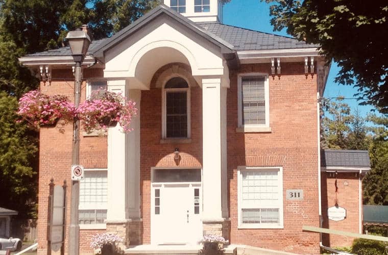 A red brick house with a two story arched front porch.