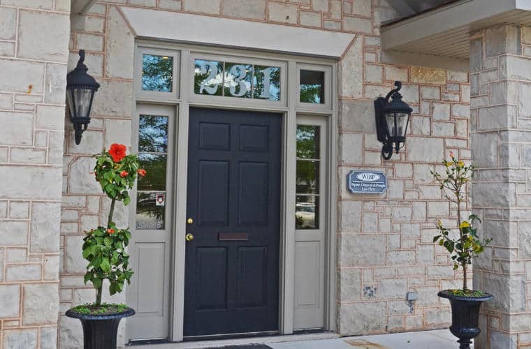 The front entrance of a rough hewn grey stone building with a Black front door.