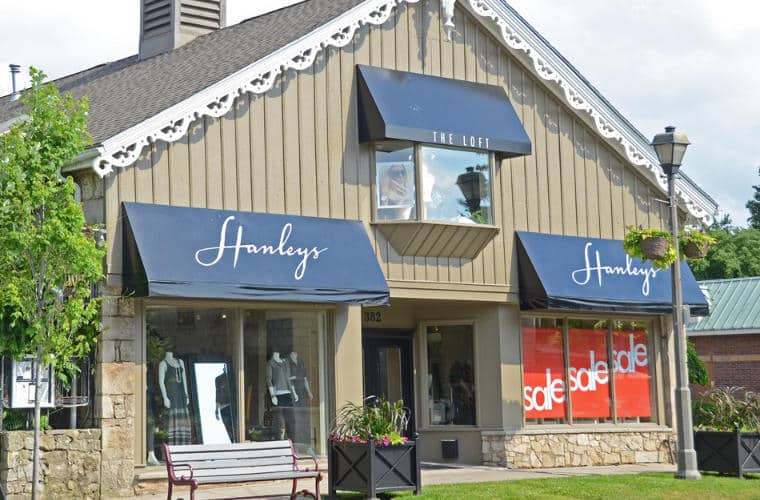 A beige 2 story building with a window wall first floor and signs for Hanley's on awnings above the windows.